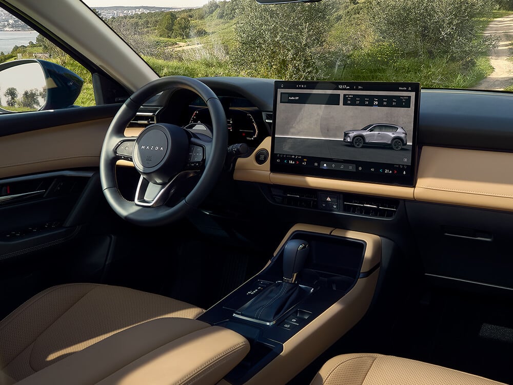 Mazda CX-5 interior showing steering wheel and display screen.
